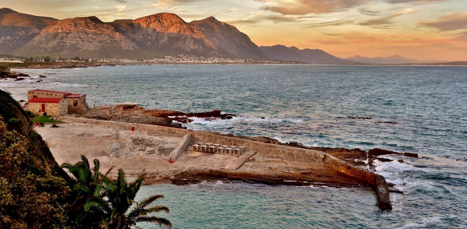 Der alte Hafen von Hermanus im Abendlicht, die Berge dahinter rot angestrahlt